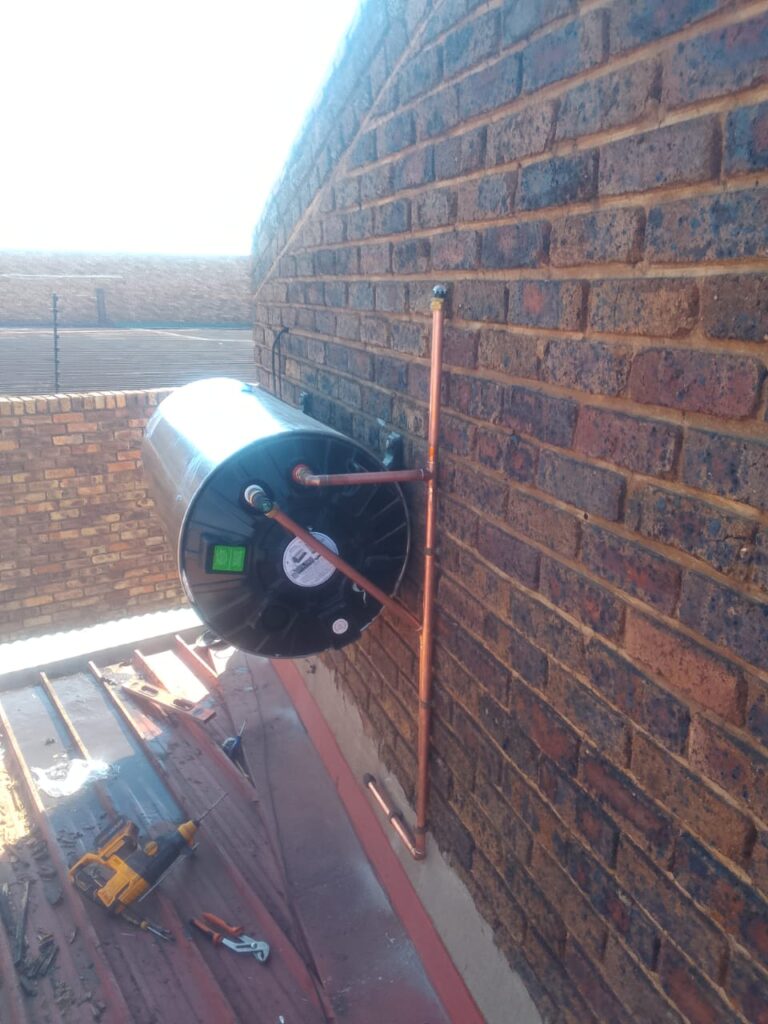 Technician installing a new geyser on a brick wall in Sandton