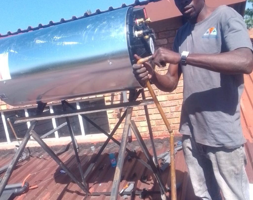 Technician repairing a solar geyser on a rooftop