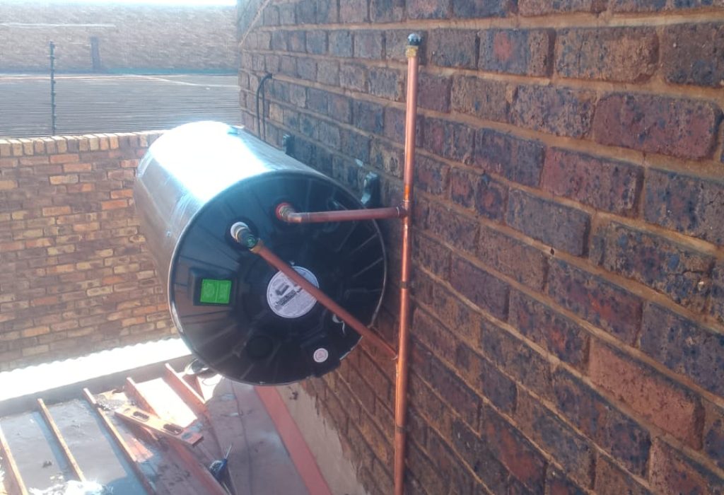 Technician installing a new geyser on a brick wall in Sandton