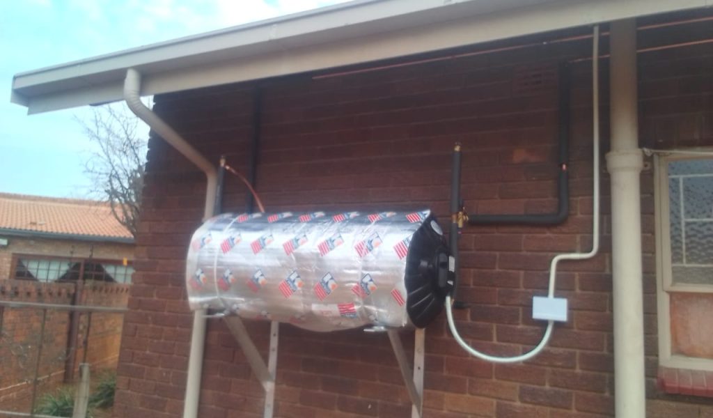 Silver geyser with insulation blanket mounted on a brick wall