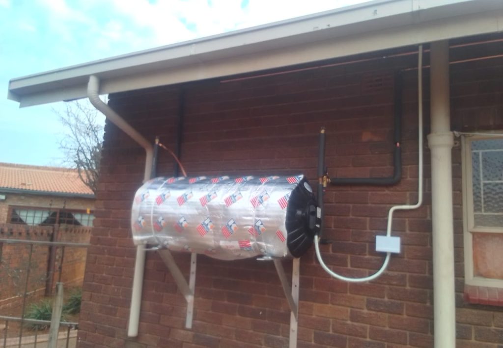 Silver geyser with insulation blanket mounted on a brick wall