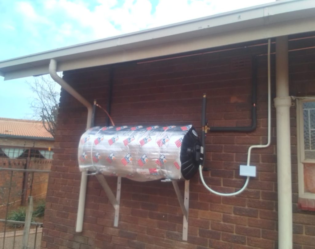 Silver geyser with insulation blanket mounted on a brick wall